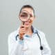 Portrait of beautiful female doctor looking through loupe